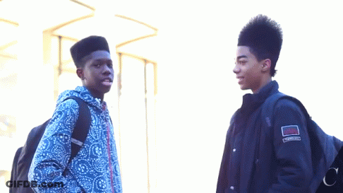 Two Young Men Standing Next To Each Other With One Wearing A Jacket That Has The Word Converse On It GIF