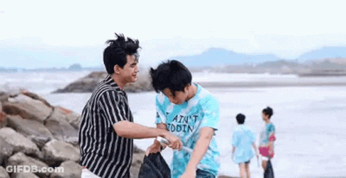 Two Young Men Standing On Rocky Beach GIF