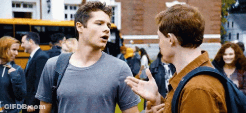 Two Young Men Talking In Front Of School Bus GIF
