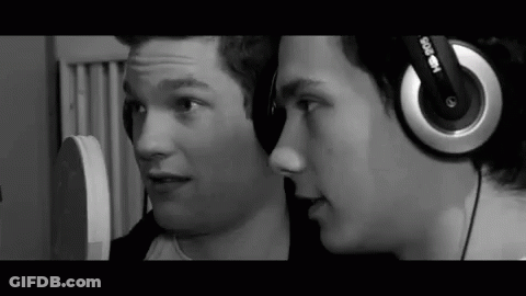 Two Young Men Wearing Headphones Talking In Black And White GIF