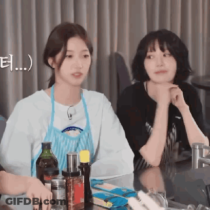 Two Young Women Are Sitting At A Table With Bottles Of Sauces And Condiments GIF