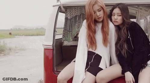 Two Young Women Are Sitting On The Back Of A Red Van . GIF