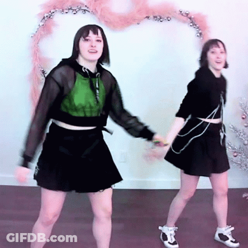 Two Young Women Dancing By Christmas Tree GIF
