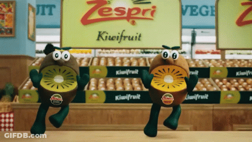 Two Zespri Kiwifruit Characters Are Dancing In Front Of A Sign For Kiwifruit GIF