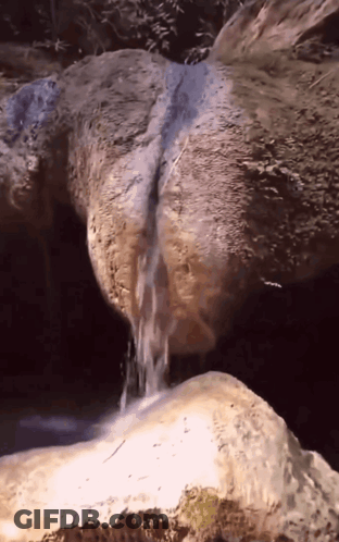 Waterfall Surrounded By Rocks And Trees GIF