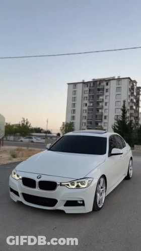 White BMW Parked In Front Of Tall Building GIF