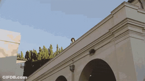 White Building With Arches And Blue Sky GIF
