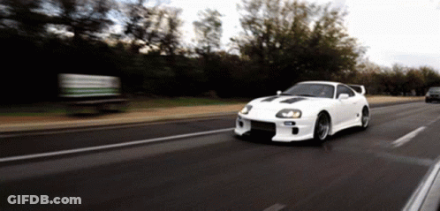 White Car Driving Down Road With Trees GIF