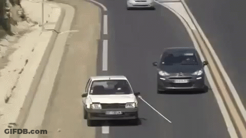 White Car Driving Next To Black Car With Stick Out Window GIF