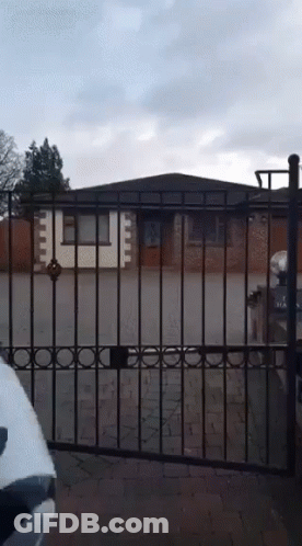 White Car Parked In Front Of Fence And Brick House GIF