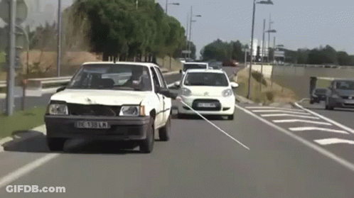 White Car With License Plate IC 389 KM Driving Down Street GIF