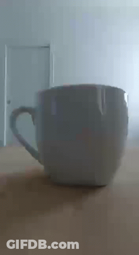 White Coffee Cup On Wooden Table In Front Of Door GIF
