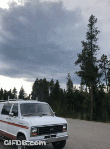 White Ford Van Parked In Lot With Trees GIF