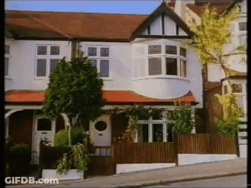 White House With Red Tile Roof And Wooden Fence GIF