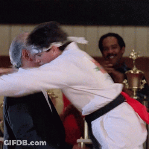 White Karate Uniform Man Hugging Black Suit Man GIF