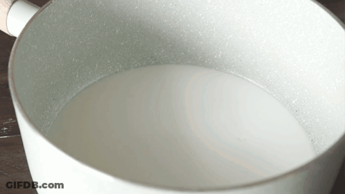 White Pot With Wooden Handle Filled With Milk GIF