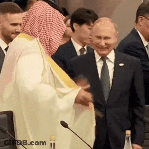 White Robe Man Shaking Hands With Suit Man GIF