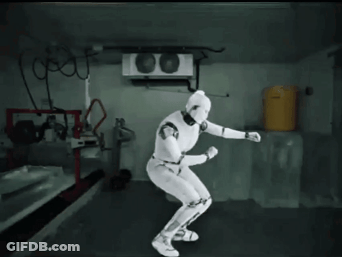 White Robot In Room With Yellow Barrel GIF