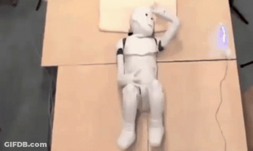 White Robot Laying On Table With Pillow GIF