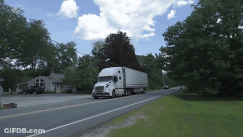 White Semi Truck Driving Down Road With Trees GIF