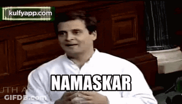 White Shirt Man With Namaskar By Wooden Wall GIF