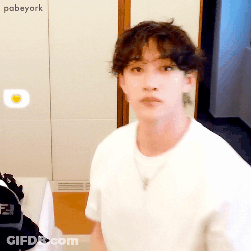 White Shirt Man With Necklace Looks At Camera GIF