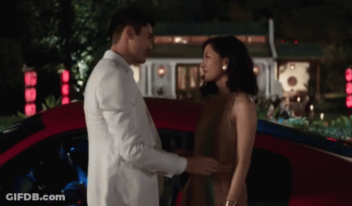 White Suit Man And Brown Dress Woman Holding Hands Red Car GIF