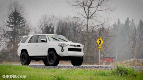 White SUV Parked Near Pedestrian Crossing Sign Saying Head GIF
