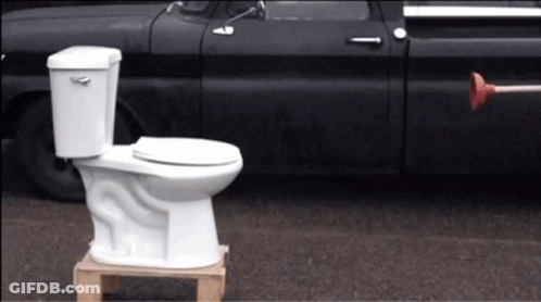 White Toilet On Wooden Pallet Next To Black Truck GIF