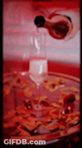 Wine Being Poured Into Glass On Tray With Flowers GIF