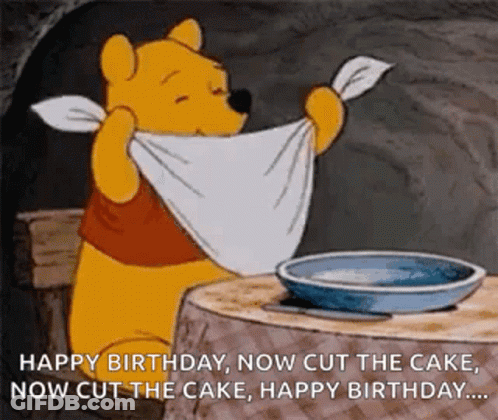 Winnie The Pooh Is Sitting At A Table With A Towel Around His Neck And A Plate Of Food . GIF