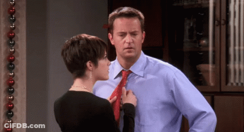 Woman Adjusting Man's Tie By Christmas Decoration GIF