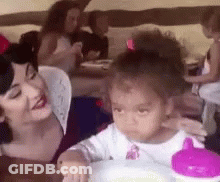 Woman And Little Girl Sitting At Table, Girl Drinking From Pink Cup GIF