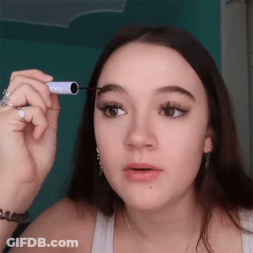Woman Applying Mascara To Eyebrows In White Tank Top GIF