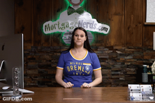 Woman At Desk In Front Of Mortgage Nerds Sign GIF
