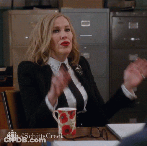 Woman At Desk With Coffee And Schitts Creek Logo GIF