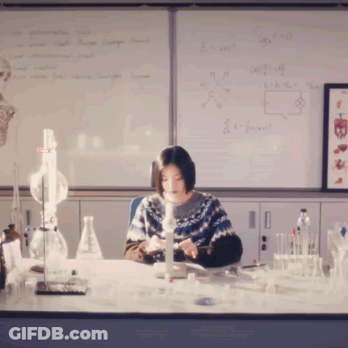 Woman At Desk With Equations On Whiteboard GIF