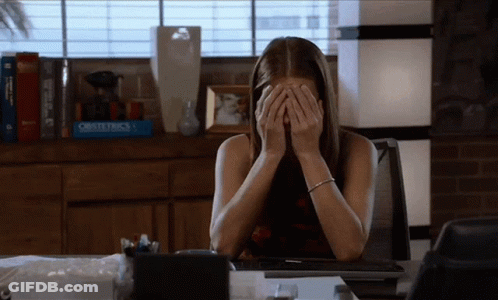 Woman At Desk With Hands On Face In Front Of Obstetrics Book GIF