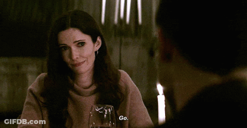 Woman At Table With Candles And Wine Says Go GIF