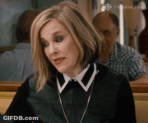 Woman At Table With Schitts Creek Logo GIF