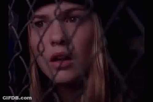 Woman Behind Chain Link Fence Looking Through GIF