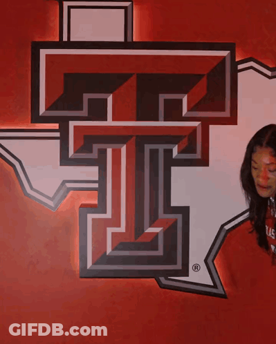Woman Beside Large T On Red GIF