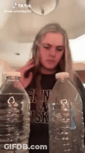 Woman Between Two Water Bottles Talking On Cell Phone GIF