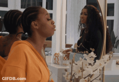 Woman Blowing Kiss In Front Of Mirror With Flowers GIF