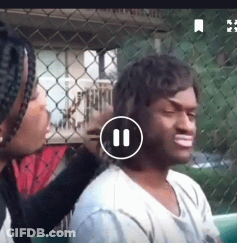 Woman Brushing Man's Hair In Front Of Chain Link Fence Playing Video GIF
