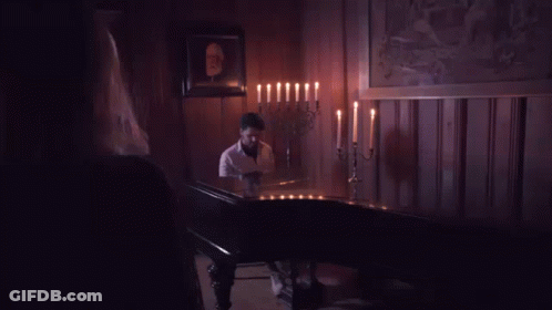 Woman By Man Playing Piano In Candlelit Room GIF