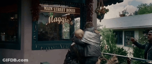 Woman Carrying Baby In Front Of Maggie's Diner GIF