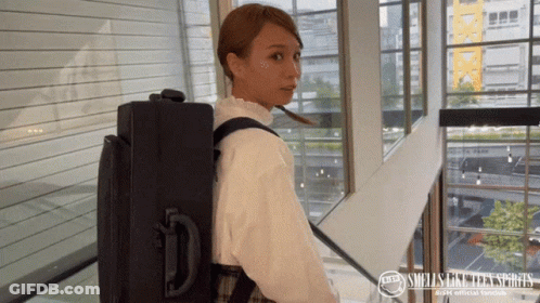 Woman Carrying Suitcase With Smells Like Teen Spirit Logo GIF