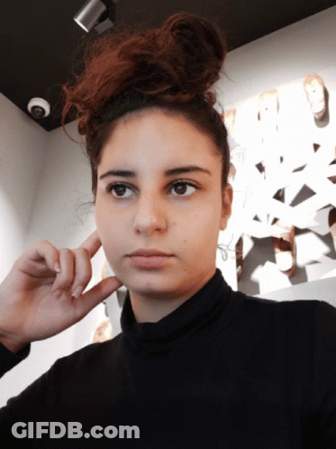 Woman Covering Ear In Black Turtleneck GIF