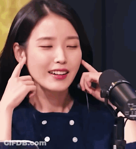 Woman Covering Ears With Eyes Closed At Microphone GIF